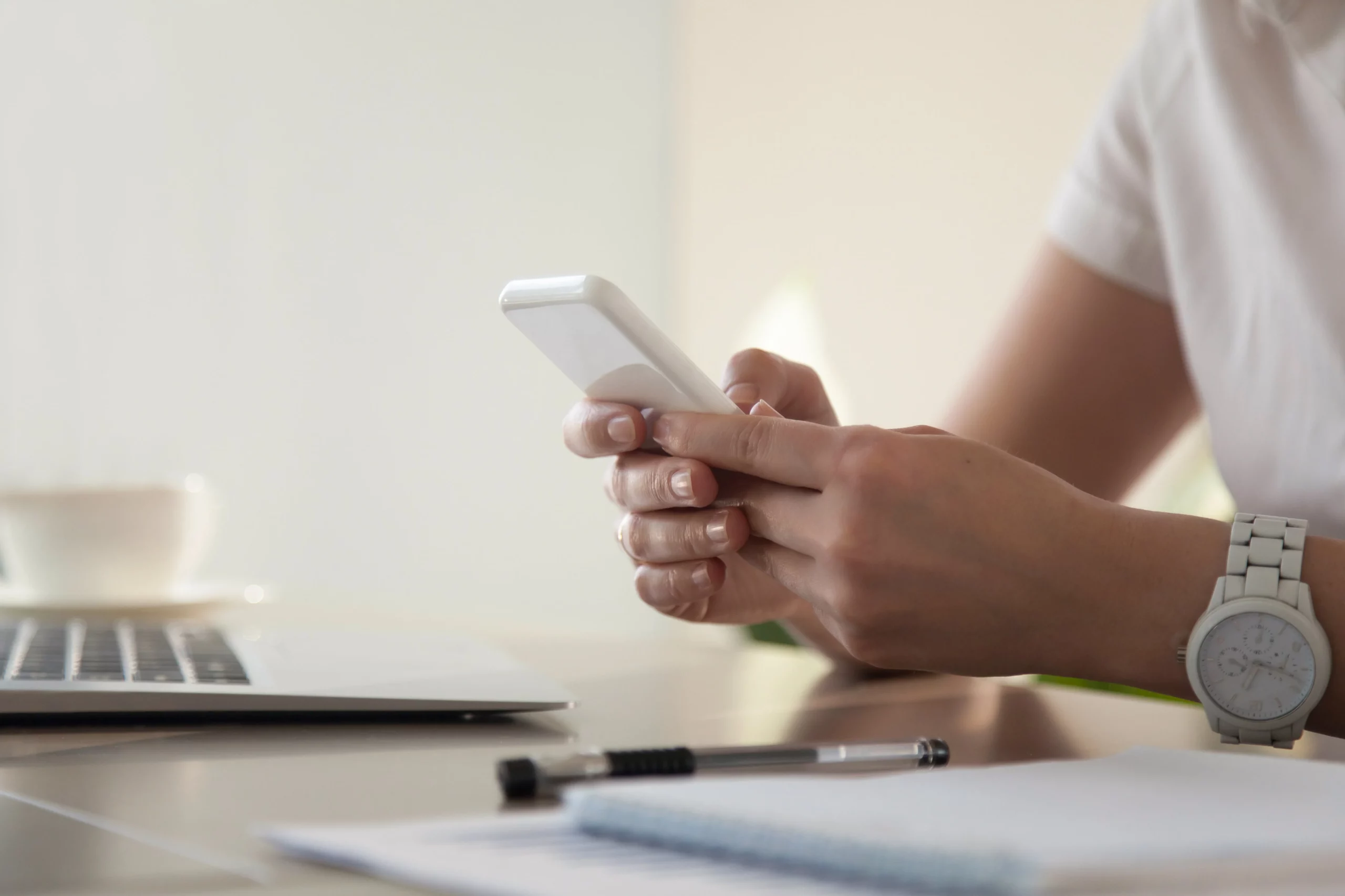 personne tenant un téléphone dans ses mains sur un bureau